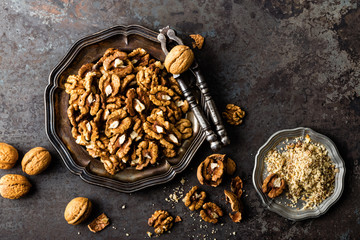 Walnut kernels and whole walnuts on rustic old wooden table