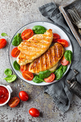 Chicken breast or fillet, poultry meat grilled and fresh vegetable salad of tomato and spinach. Healthy diet menu for lunch