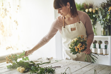 Young woman making a floral arrangement in her flower shop