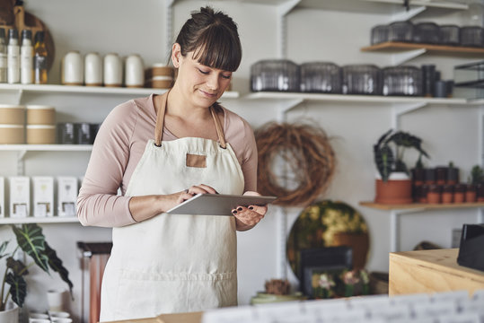 Smiling Florist Working In Her Flower Shop Checking Online Orders