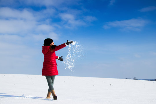 Woman is playing with snowball. Young woman enjoying from snow during a sunny day at winter . 