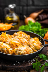 Cabbage rolls stewed with meat and vegetables in pan on dark wooden background