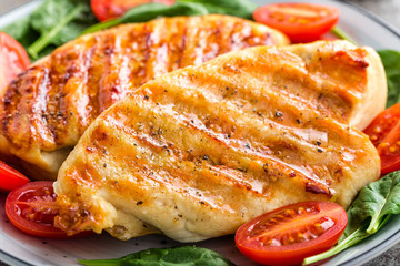 Chicken breast or fillet, poultry meat grilled and fresh vegetable salad of tomato and spinach. Healthy diet menu for lunch