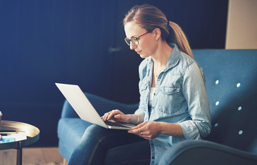 Focused young businesswoman sitting at home working on a laptop