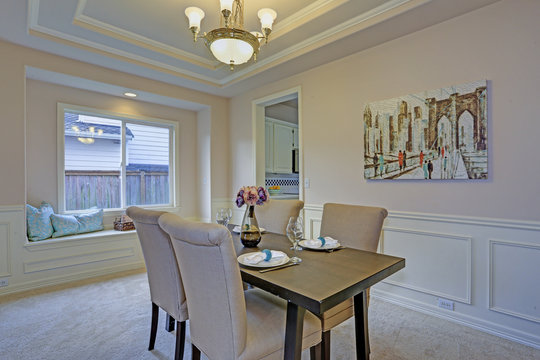 Chic dining room accented with wall panel mouldings and tray ceiling.