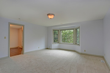 Empty room with white walls flanking a bay window