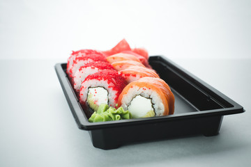 Beautiful rolls in black container on white background with reflection, for a menu or website