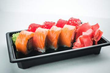 Beautiful rolls in black container on white background with reflection, for a menu or website