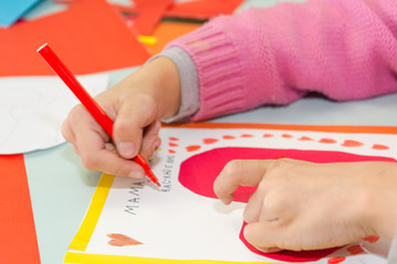 Child draw a postcard. Children are engaged in needlework. The girl signs a postcard on 14 February.