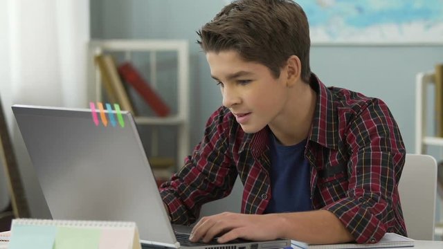 Teenager successfully doing practical work for programming lesson using laptop
