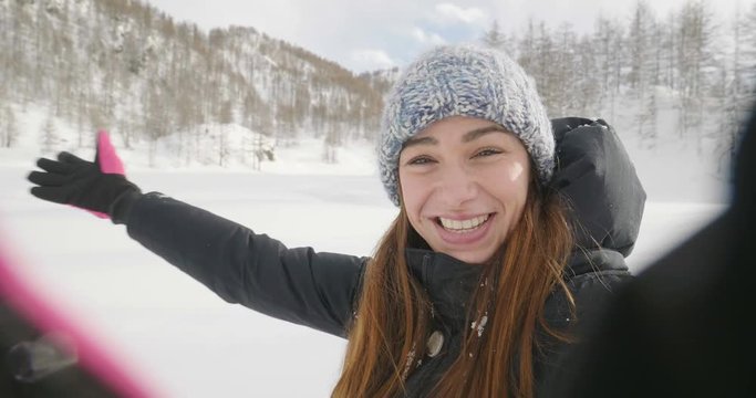 On a winter day, a woman in the mountains makes a video call and greets his husband or friends on the phone. Concept of: winter holidays, technology, christmas, connection