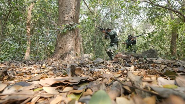 Squad of Fully Equipped and Armed Soldiers moving through Forest with Rifle Ready To Shoot in Slow motion.