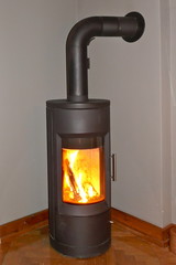 Ein moderner,brennender, schwarzer, eiserner Kaminofen mit Schornstein steht im Wohnzimmer in einer...