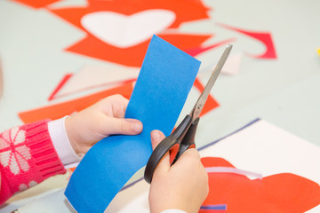 The child cuts out of paper. The child is engaged in needlework.