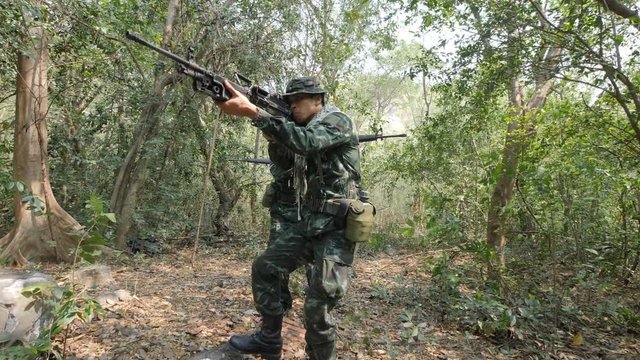 Squad of Fully Equipped and Armed Soldiers moving through Forest with Rifle Ready To Shoot.