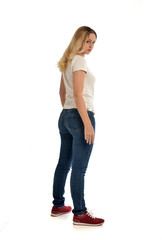 full length portrait of blonde girl wearing simple shirt and jeans, standing pose on white background.