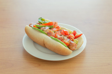 Bacon-Wrapped Hot Dog with bacon wrapped sausage, mayonnaise, sauteed onions and peppers, tomato with cilantro, hot pepper and bacon bits.