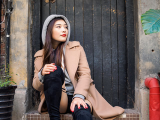 Portrait of a sexy Chinese young girl sit against wooden door in Shanghai Xintiandi.