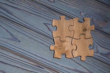Concept of collected pieces of puzzles on the wood texture background. Idea: Cooperation, strategy,...