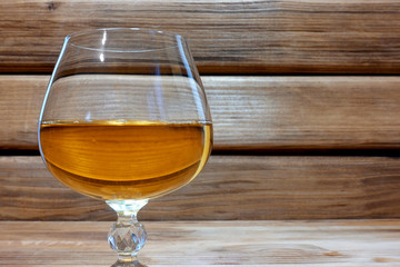Glass of cognac or brandy with space for text on a wooden background.    