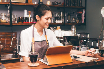 Barista woman using digital tablet compute in coffee shop counter bar