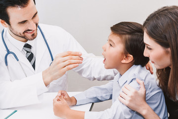 Fototapeta premium Doctor having throat examined checking little boy in hospital.healthcare and medicine