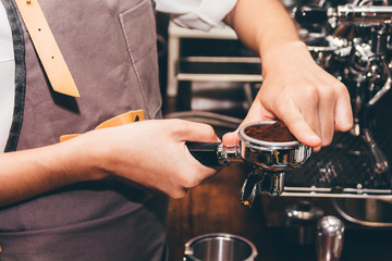 Women Barista using coffee machine for making coffee in the cafe