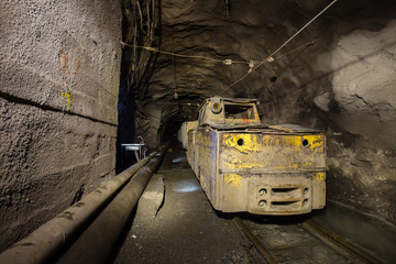 Underground iron ore mine shaft tunnel gallery with electrical locomotive