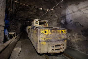 Underground iron ore mine shaft tunnel gallery with electrical locomotive