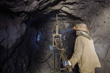 Underground iron ore mine shaft tunnel gallery with miners drilling