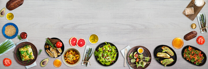 Fresh and cooked vegetarian meal and products. Concept of healthy organic food. White wooden table. Top view. Wide panoramic image. Copy space. Wide panoramic image