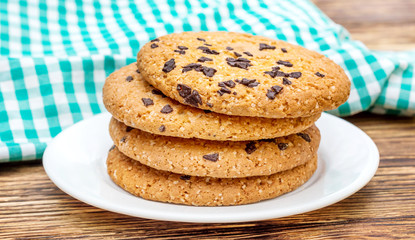 Cookies with chocolate on plate with kitchen towel on the table.