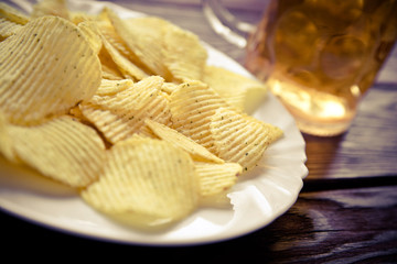 Potato chips and beer on a wooden table 