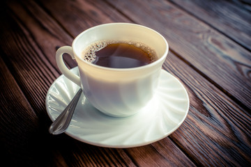 A cup of hot coffee stands on a wooden table 