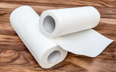 Two paper kitchen towels on the brown wooden table.