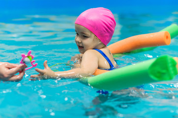 A little girl of European appearance floating in the pool on inflatable toy