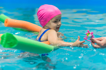 A little girl of European appearance floating in the pool on inflatable toy