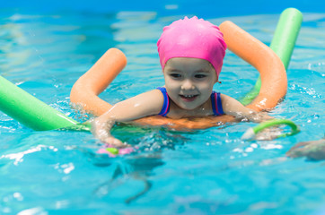A little girl of European appearance floating in the pool on inflatable toy
