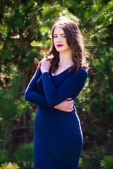 Beautiful fashion model in a dress in a green park in the summer . Blue dress.