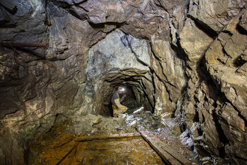 Underground abandoned gold ore mine shaft tunnel gallery with miners