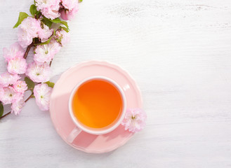 Cup of tea and  blossoming Almond (Prunus triloba) branch  on rustic table.