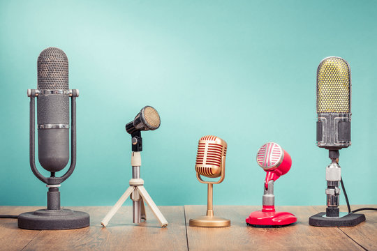 Retro old microphones for press conference or interview recording on wooden table front gradient aquamarine wall background. Vintage old style filtered photo