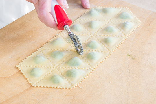 Traditional Italian pasta. Preparation phase of tortelli with spinach and ricotta using a dough cutter (cutter wheel)