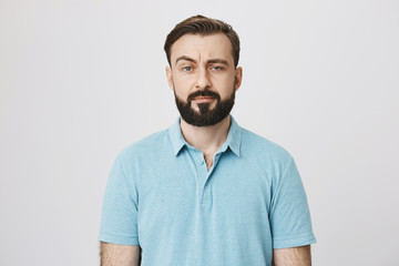 Fototapeta premium Portrait of a mature man with a beard and moustache looking suspicious. Person lifts his eyebrow and do not really believe in the words he hears, looking a little bit gloomy.