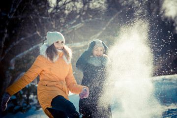 Girl in winter. A young girl is having fun in a winter park with friends. Active rest in winter. Young woman in a yellow coat against snowy background. students playing with snow
