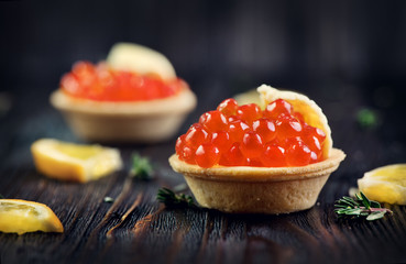 Tartlet with salmon caviar closeup. Snacks with trout caviar, appetizer