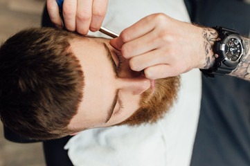 Close up image of barber makes beard cut of a man