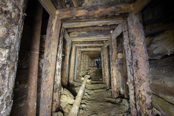 Fototapeta na wymiar Underground abandoned ore mine shaft tunnel gallery with wooden timbering