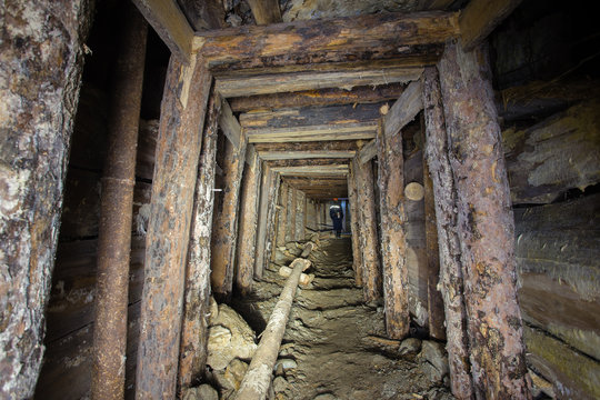 Underground abandoned ore mine shaft tunnel gallery with wooden timbering
