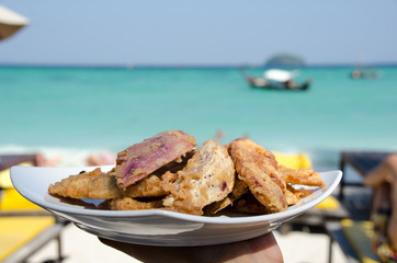 Fried banana in plate with woman hand ,seaside